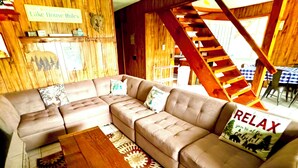 Un interno in legno con un divano modulare in pelle marrone, un tavolino in legno e una scala.