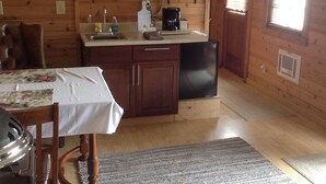 A wooden cabin interior with a kitchen area, a dining table, and a microwave.