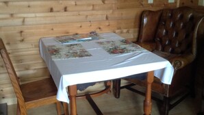 A wooden interior with a table covered by a white tablecloth, a brown leather chair, and a wooden bench.