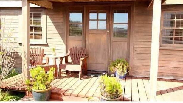 A wooden deck with a covered porch, two doors, and two windows.