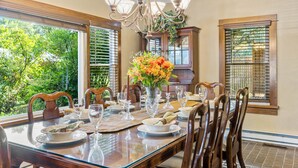 Comedor con una mesa grande dispuesta para seis personas, rodeada de sillas de madera.