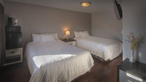 A hotel room with two beds, a nightstand with a lamp, a microwave, and a vase with flowers. - Spirit Lake Resort Motel (Menahga)