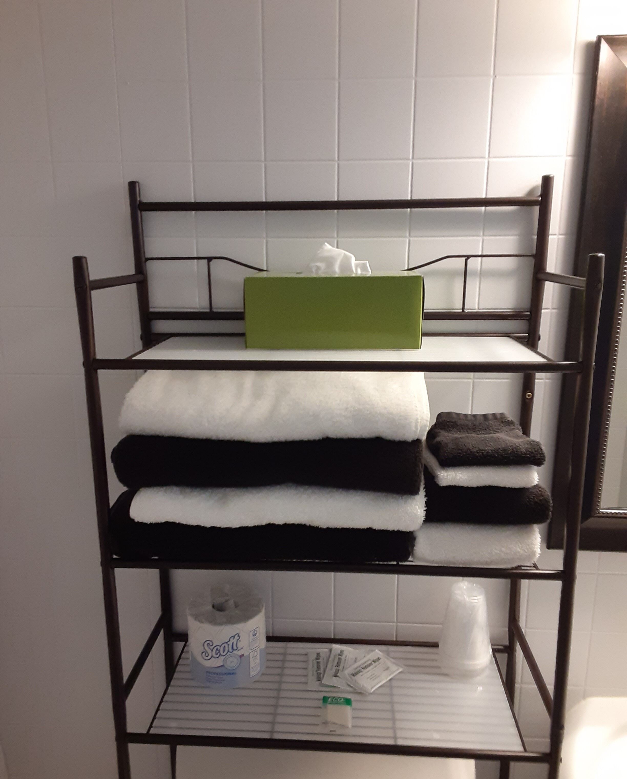 A metal shelf with towels and toiletries.