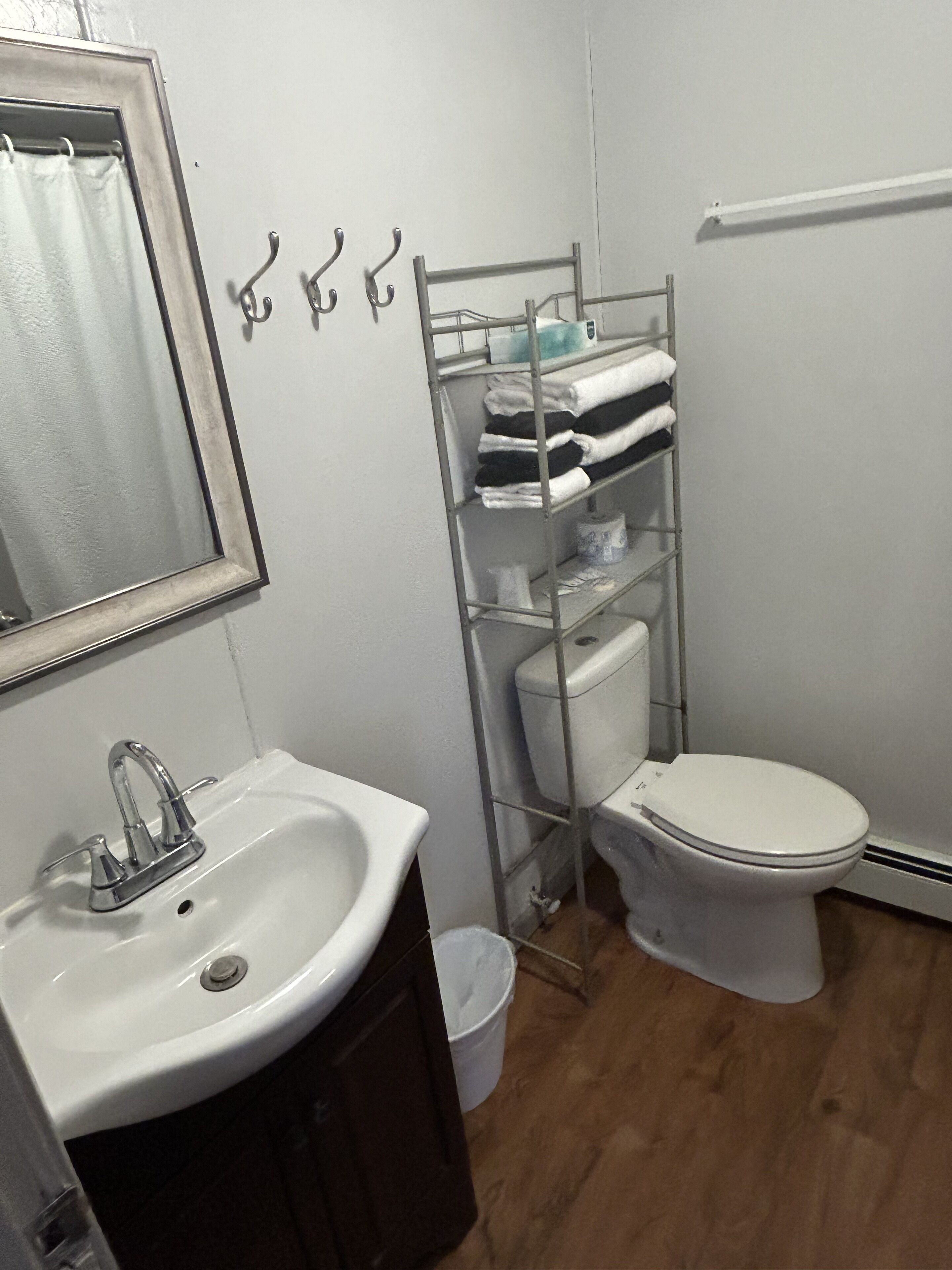 Une petite salle de bain avec un lavabo blanc, un miroir, des toilettes et un porte-serviettes en métal.