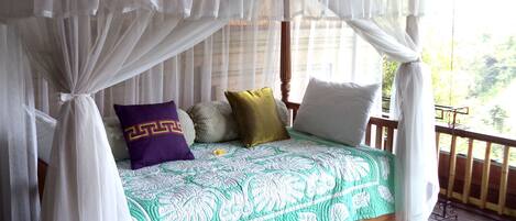 A bed with a canopy, pillows, and a green patterned bedspread.