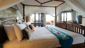 A spacious bedroom with a canopy bed, a balcony view, and a wooden headboard. - Sunrise Villa Ubud (Ubud)