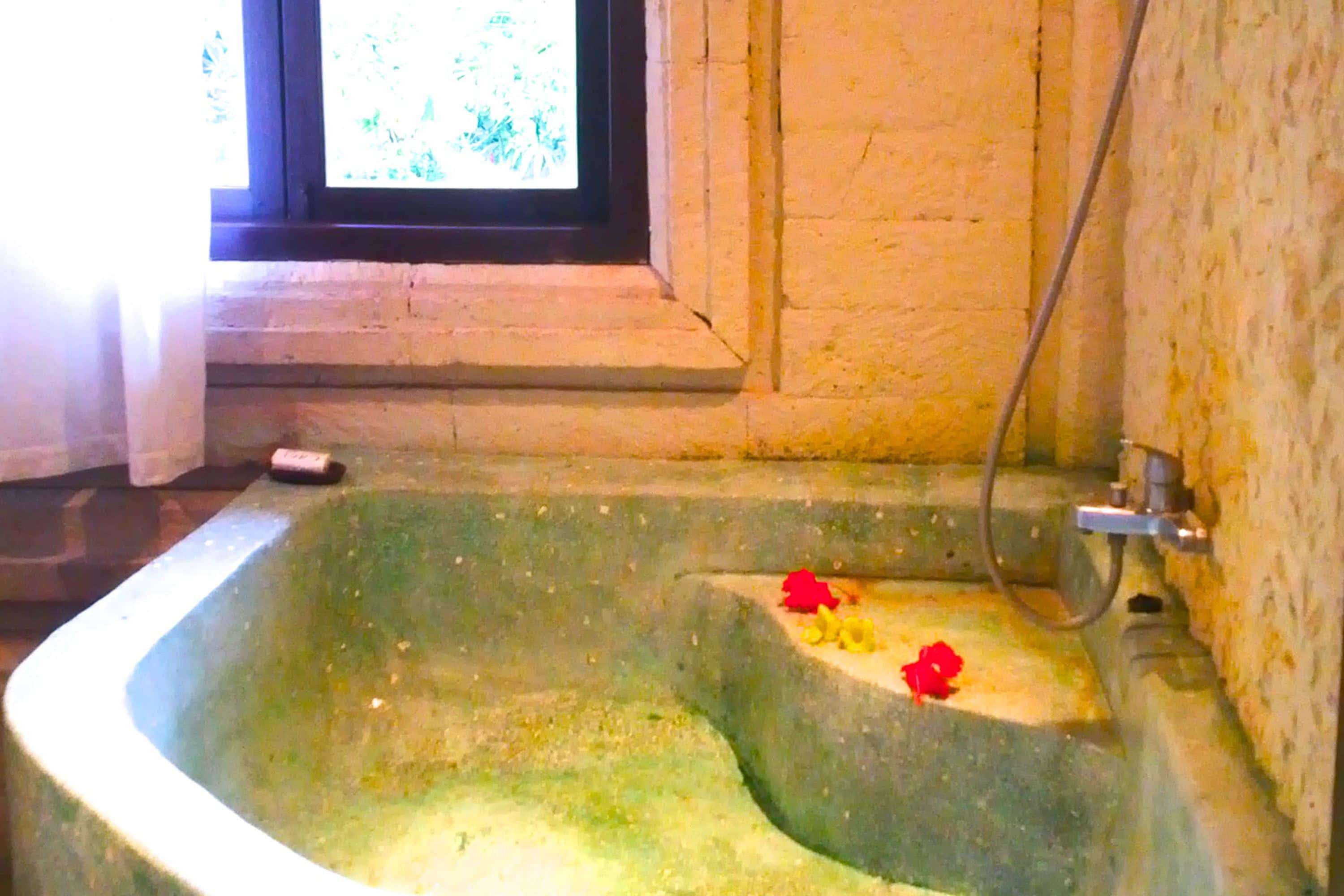Eine Steinbadewanne mit einem Fenster darüber.