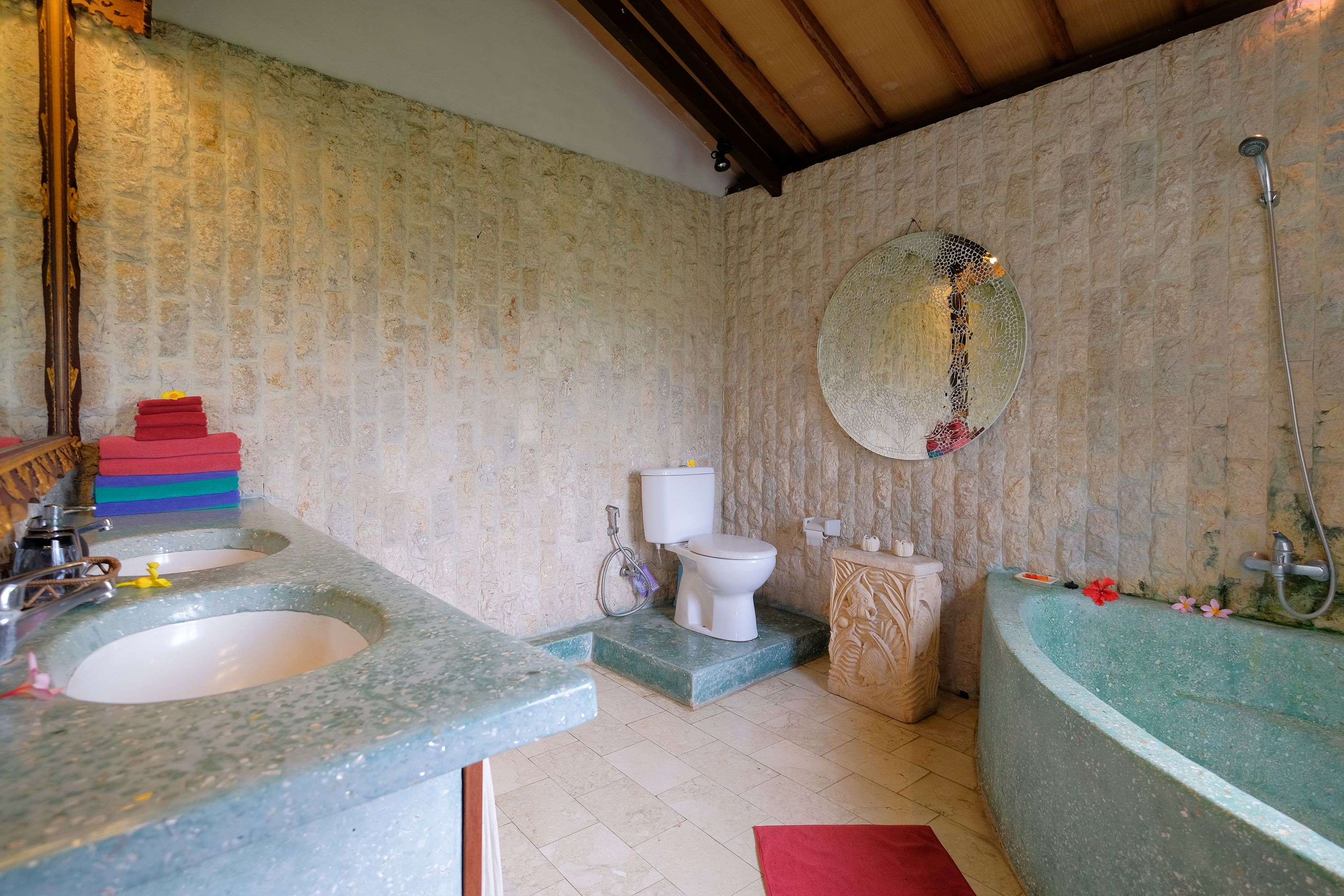 A bathroom with a stone sink, toilet, and bathtub.
