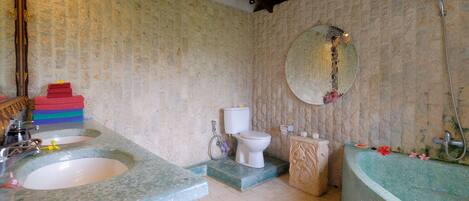 A bathroom with a stone sink, toilet, and bathtub.