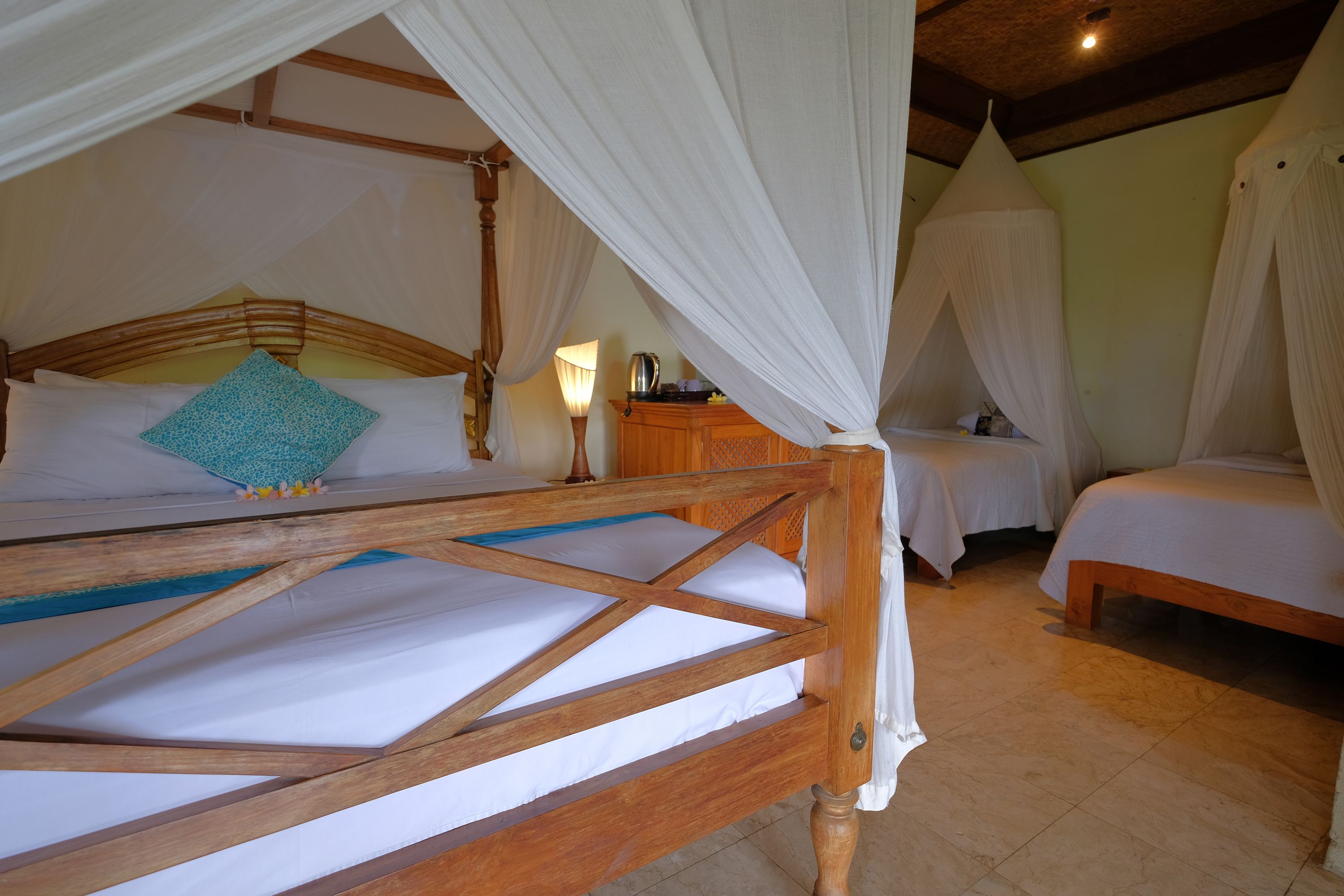 A room with a wooden bed, a smaller bed, and a nightstand with a lamp.