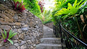 A stone staircase with a metal handrail, surrounded by lush green foliage. - Sunrise Villa Ubud (Ubud)