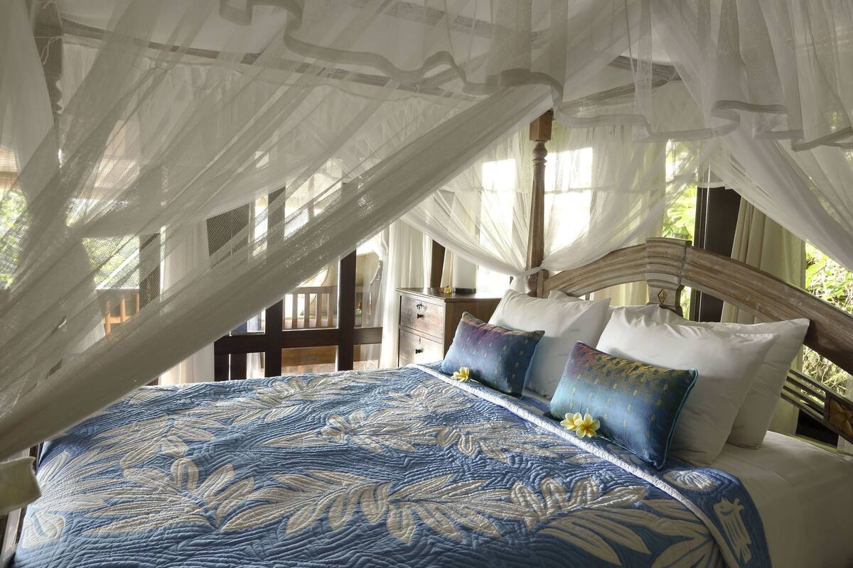A bed with a canopy, pillows, and a floral-patterned bedspread.
