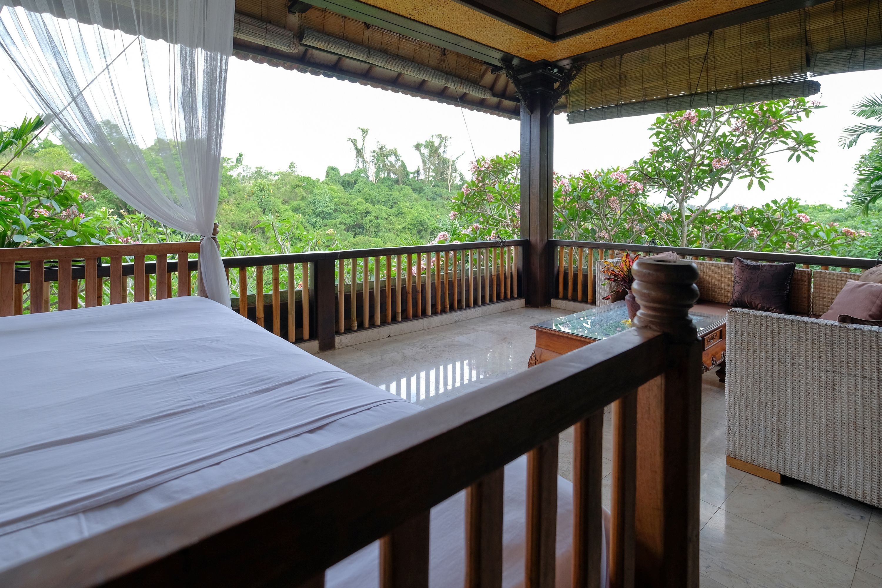 A balcony with a wooden railing, a wicker sofa, and a glass-top table.