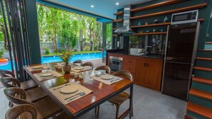 A modern kitchen with wooden cabinets, a built-in oven, and a refrigerator. - Chay Villas An Bang (Da Nang)