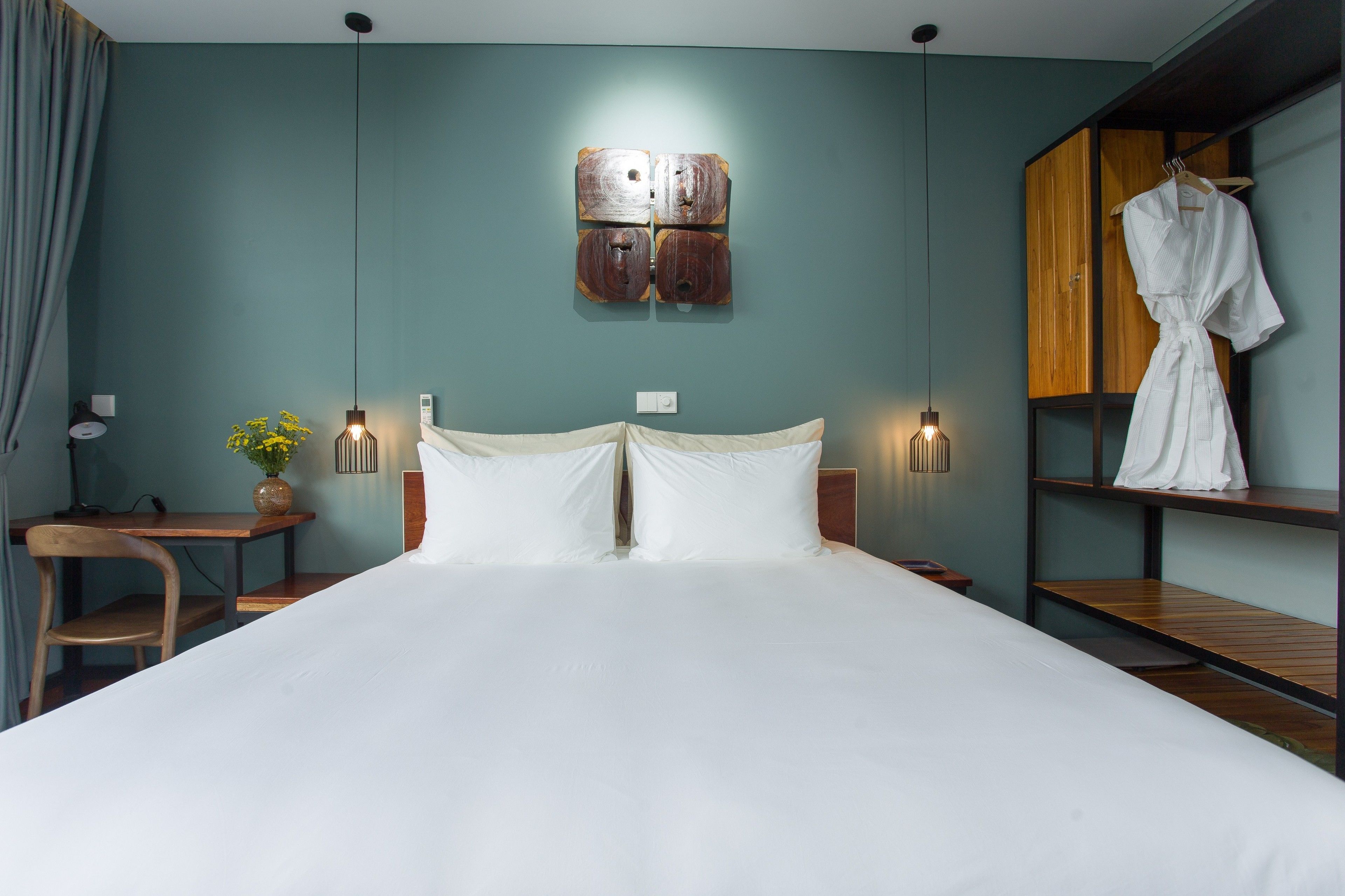 A neatly arranged hotel room with a large bed, bedside tables, a desk, and a wardrobe.