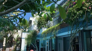 An outdoor swimming pool with a pink flamingo float, surrounded by lush greenery and modern architecture. - Chay Villas An Bang (Da Nang)