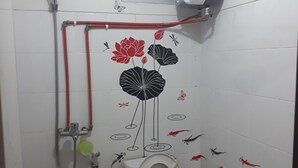 Een badkamer met toilet, douche en een luchtverfrisser aan de muur.