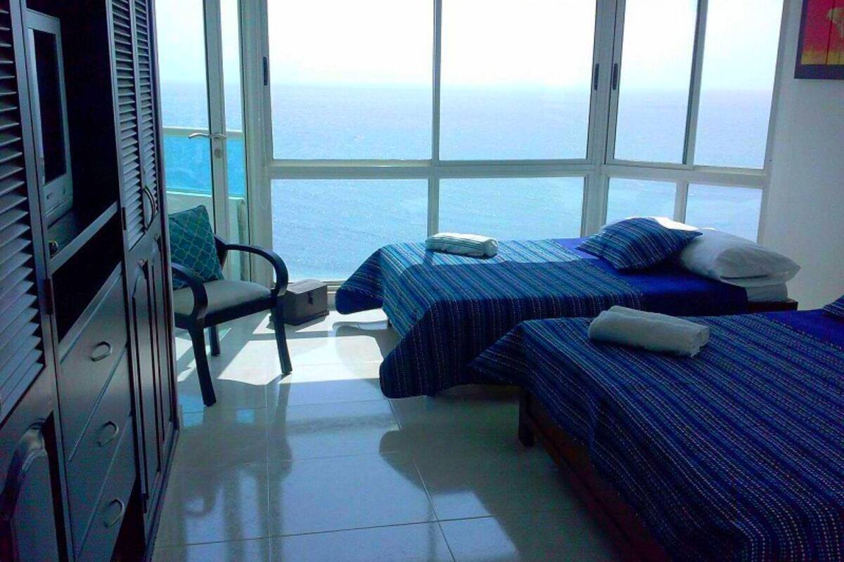 A room with two beds, a chair, and a TV.