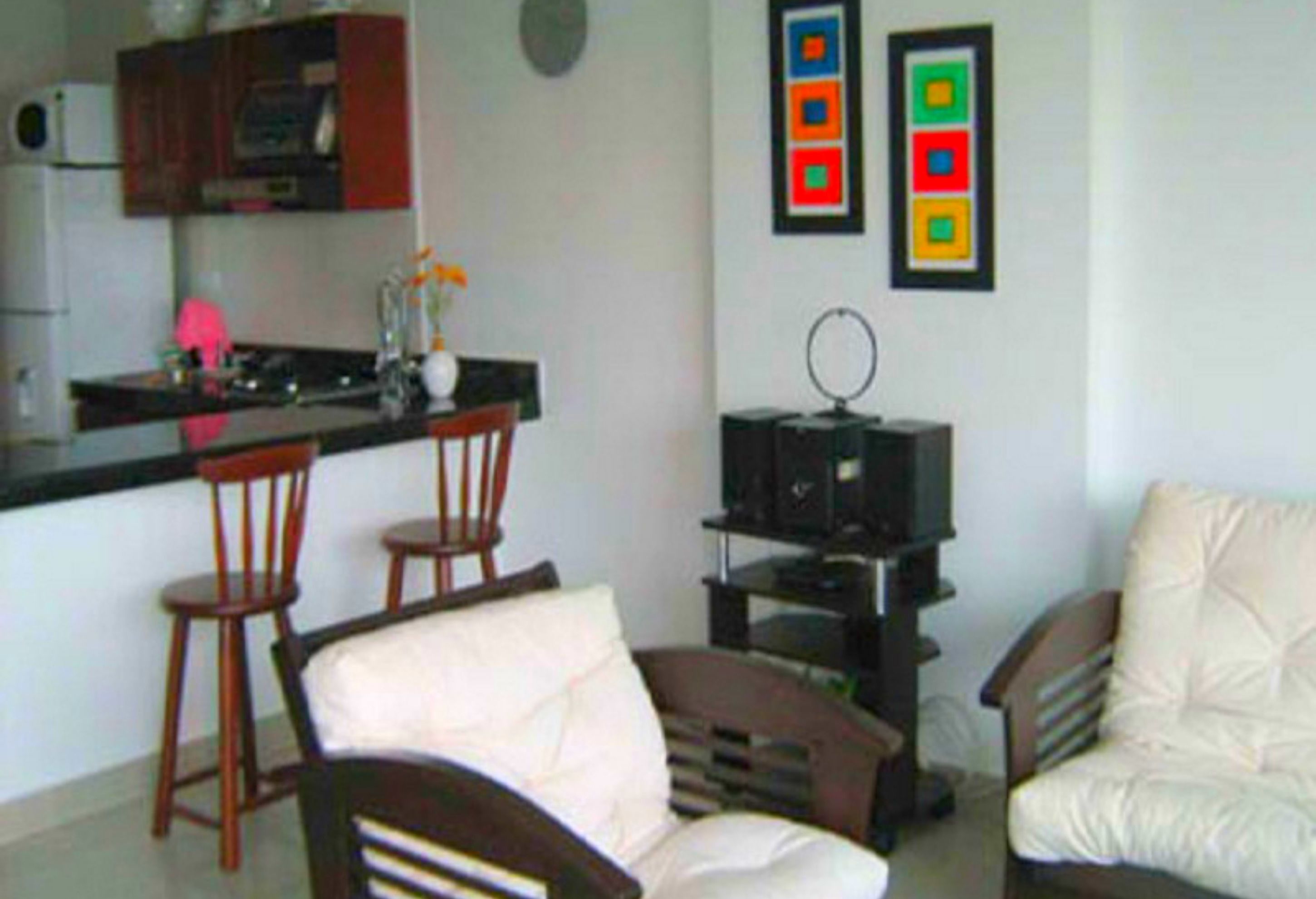 A compact living space with a kitchenette, a dining area with two chairs, a sofa, and a television on a stand.