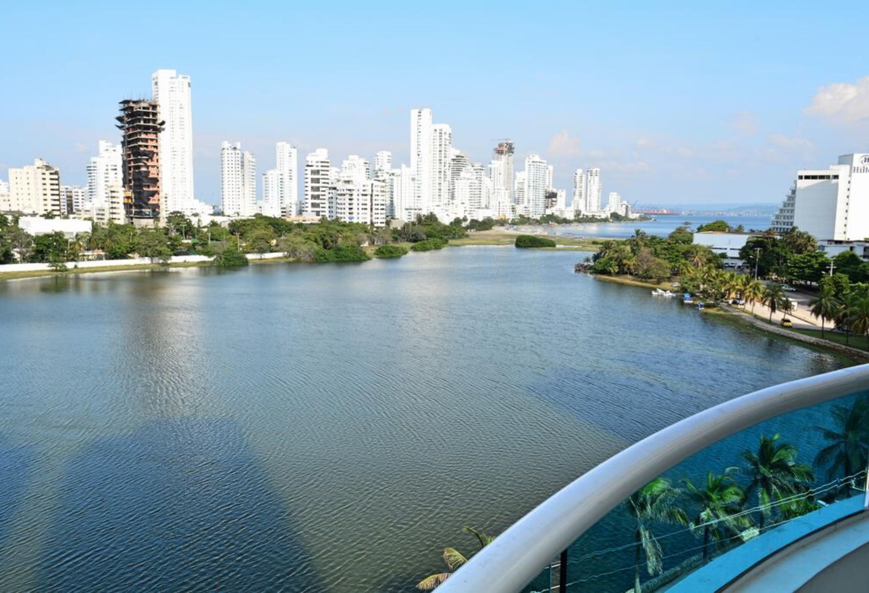 A waterfront view of a cityscape with modern buildings, a river, and a bridge.