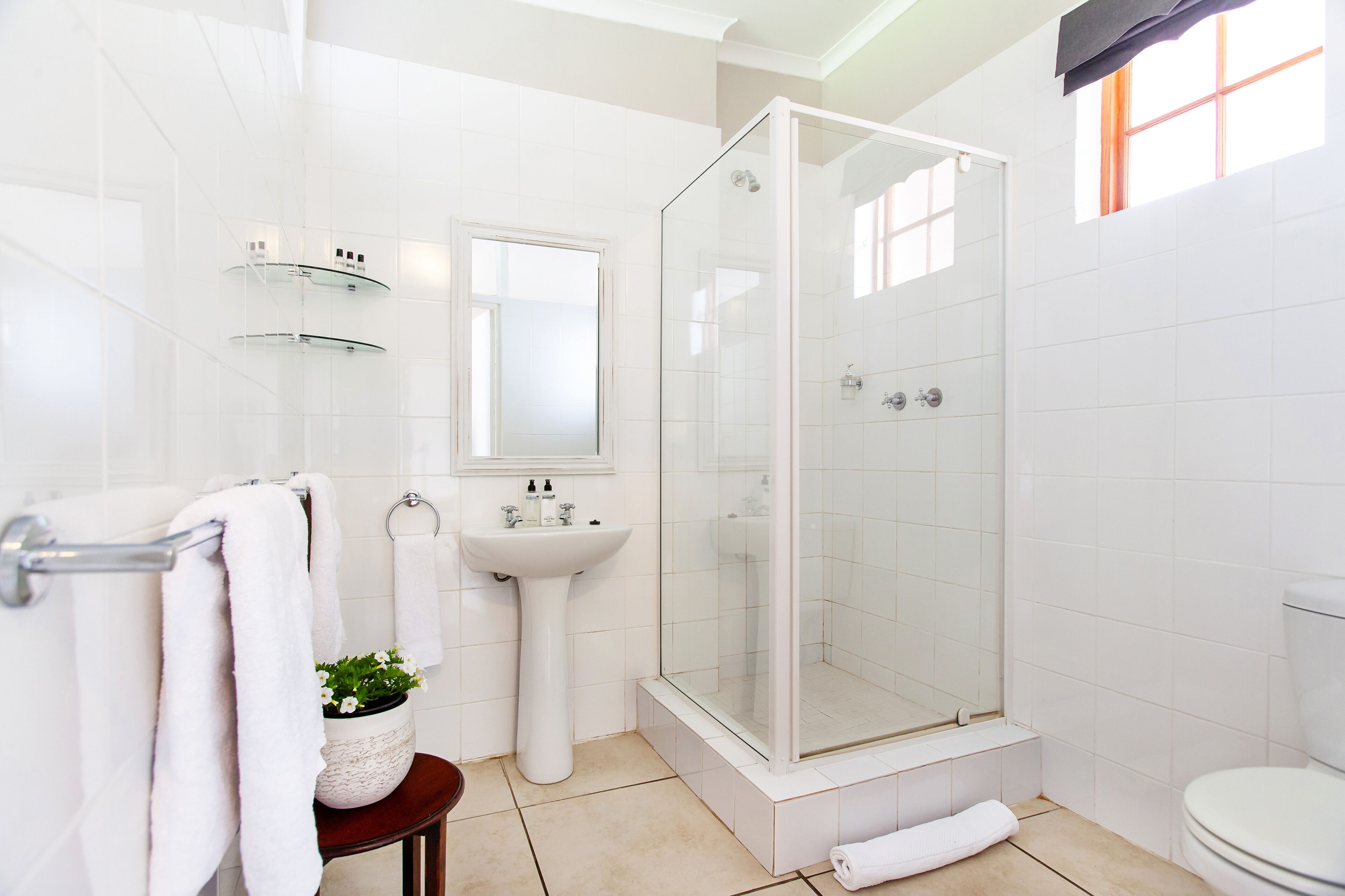 A modern bathroom with a glass-enclosed shower, a pedestal sink, and a toilet.