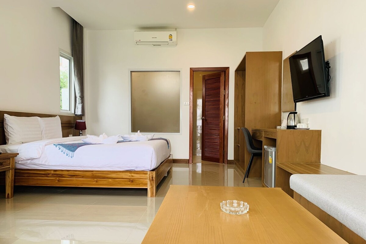 Een hotelkamer met een bed, een bureau, een televisie en een koffiezetapparaat.