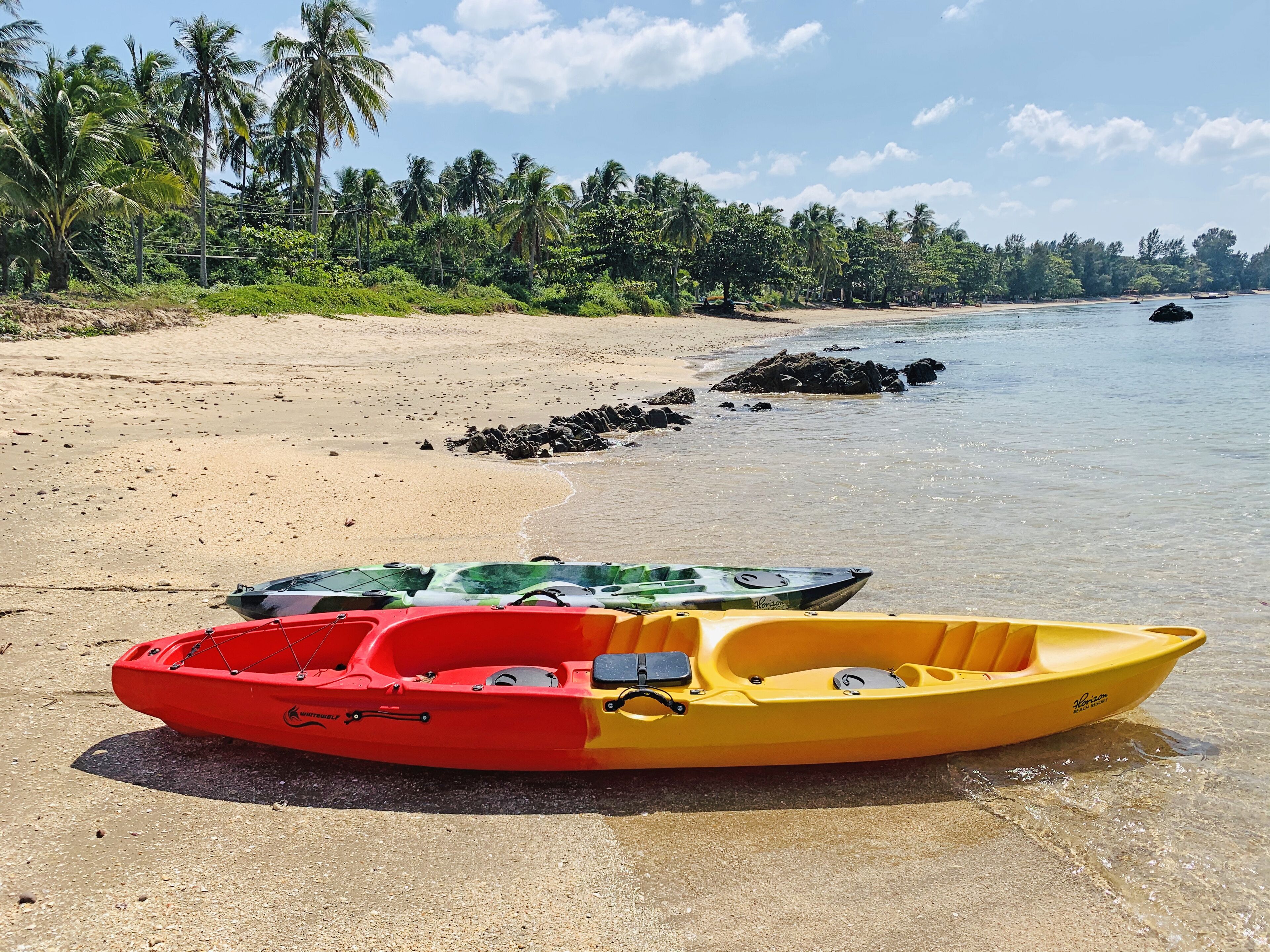 A beach with kayaks and a clear view of the ocean.