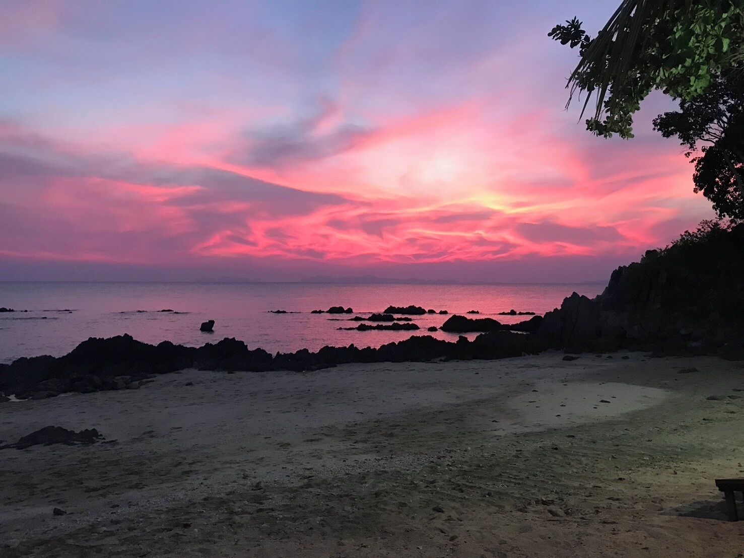 A beach with a rocky shoreline and a sunset in the background.