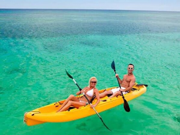 Dos personas en un kayak amarillo sobre aguas turquesas transparentes.
