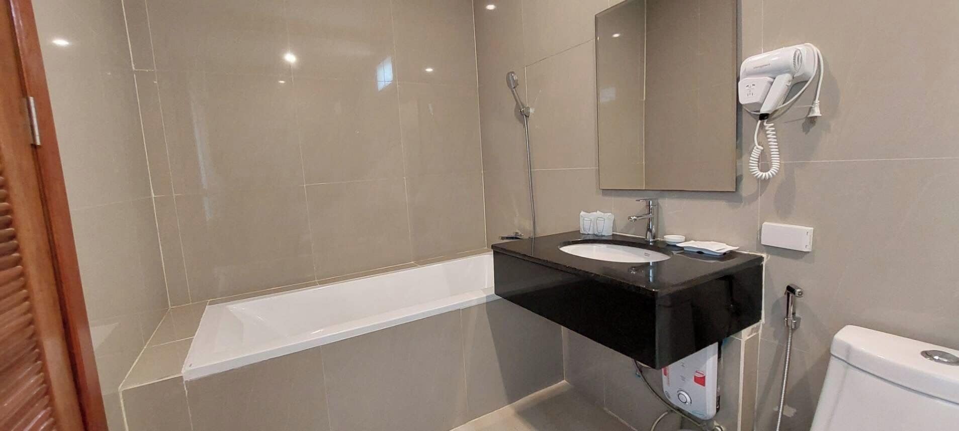 A modern bathroom with a black sink, a mirror, a handheld showerhead, and a toilet.