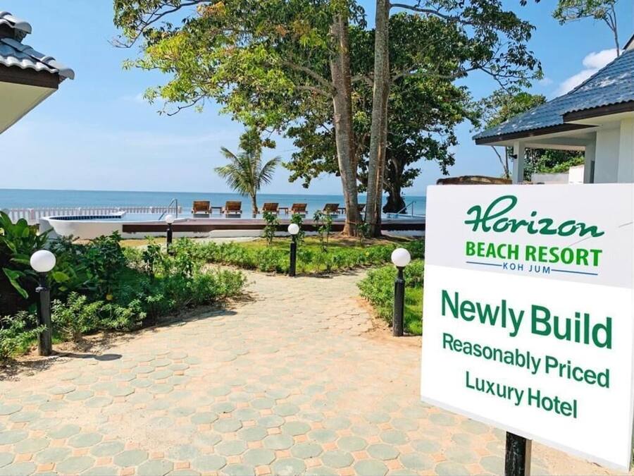 A pathway leading to a beach resort with a sign indicating a newly built luxury hotel.