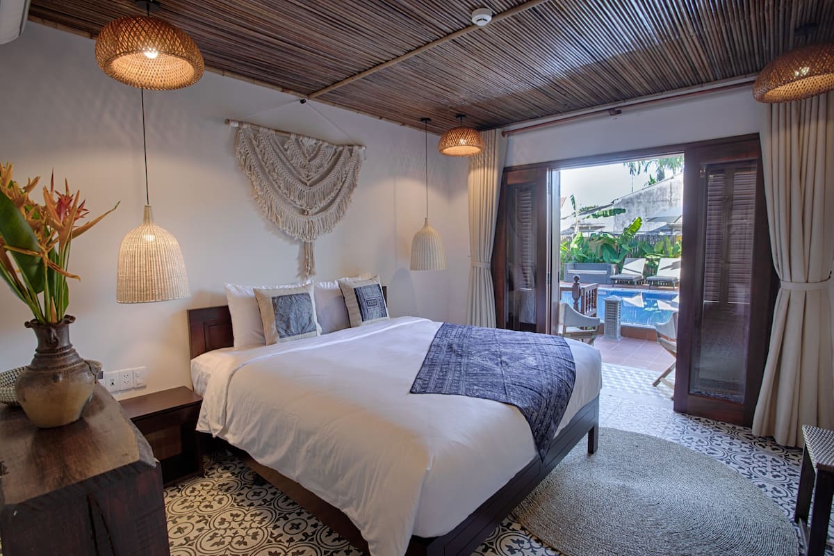 A bedroom with a large bed, a view of the pool, and a balcony.