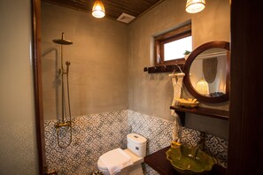 A bathroom with patterned tiles, a toilet, a sink with a decorative basin, and a shower with a handheld showerhead. - An Sen Boutique Villas (Da Nang)