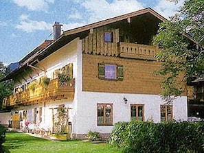 A traditional two-story house with a balcony, a chimney, and a well-maintained garden. - Ferienwohnung Untersberg, 1 bis 2 Personen, 56 qm, 1 Schlafzimmer, Balkon (Schönau am Königssee)