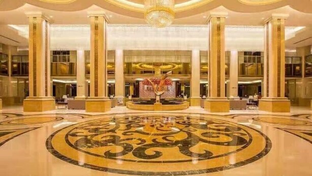 Un lobby espacioso con techos altos, columnas ornamentales y una fuente central.