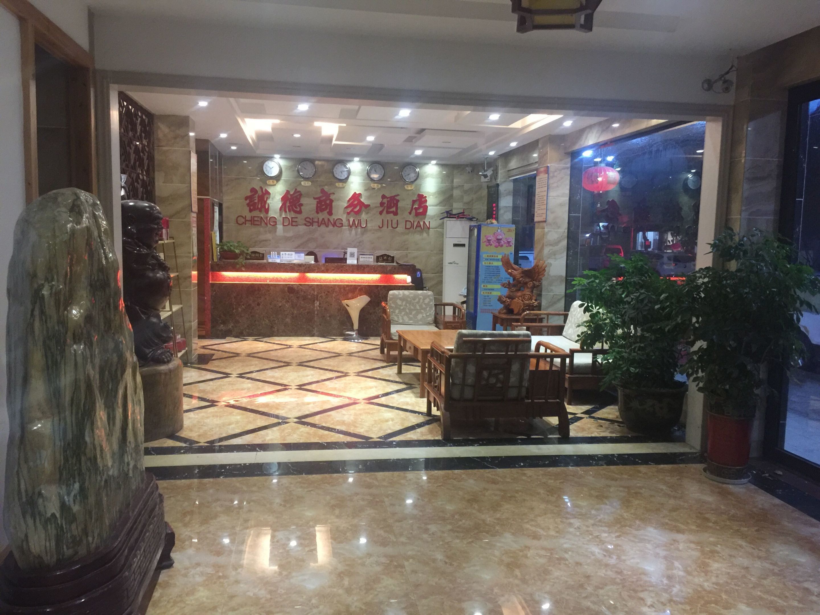 A hotel lobby with a reception desk, seating area, and a statue.