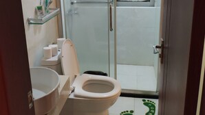 Un baño con inodoro, lavabo, cabina de ducha de vidrio y toallero.