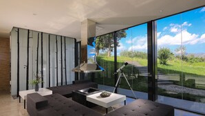 A modern living room with a large glass wall, a sofa, a coffee table, and a telescope. - The Rock Hotel (Lijiang)