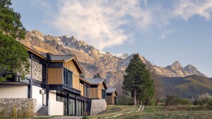 A modern building with a stone facade, wooden accents, and a staircase leading to a covered entrance. - The Rock Hotel (Lijiang)