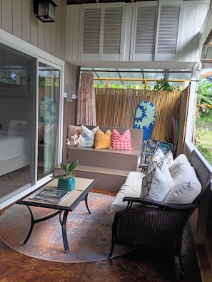 En overdækket terrasse med en sofa, et bord og en stol.