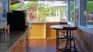 Una cocina con armarios de madera, encimera de granito, comedor con mesa y sillas, y vista a zonas verdes al exterior.