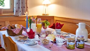 A breakfast table set with various food items, including bread, fruits, and condiments. - Bauernhof Buchwieser (Unterammergau)
