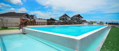 A rectangular swimming pool with a wooden deck and a grassy area on one side.