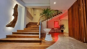 Una escalera moderna con escalones de madera y barandilla de metal, que sube a un segundo piso.