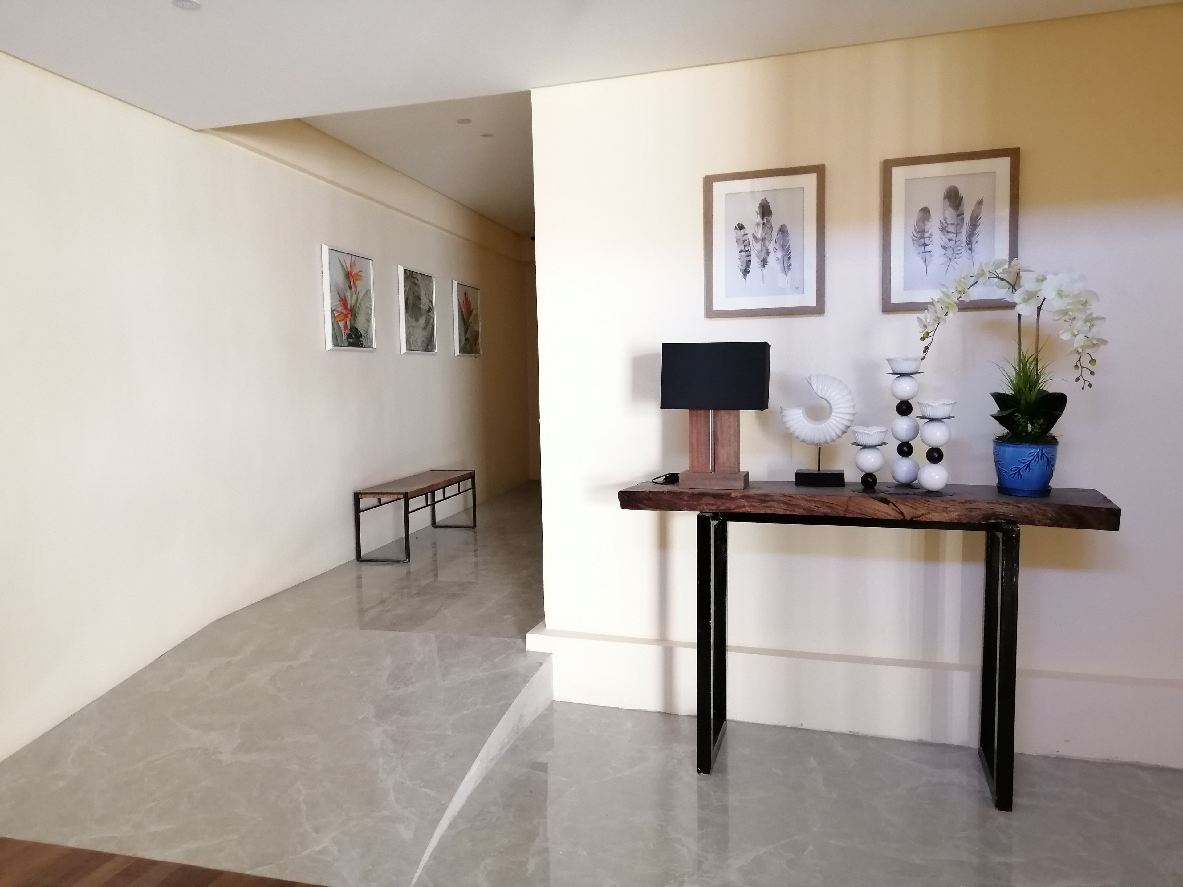 A hallway with a wooden console table, a black lamp, and framed artwork on the wall.