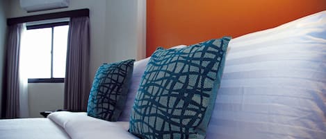 Una cama bien hecha con sábanas blancas y dos almohadas estampadas.