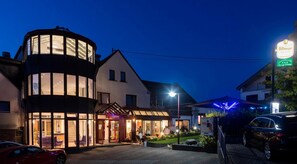 A hotel with a modern design, featuring a curved glass facade and a traditional building with a pitched roof. - Landhotel Wolf-Mertes (Sessenbach)
