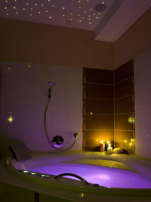 A modern bathroom with a freestanding bathtub, a handheld showerhead, and a wall-mounted faucet.