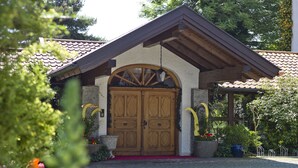 A building with a wooden door, a red carpet, and potted plants. - Appartementhof Aichmühle (Bad Fuessing)