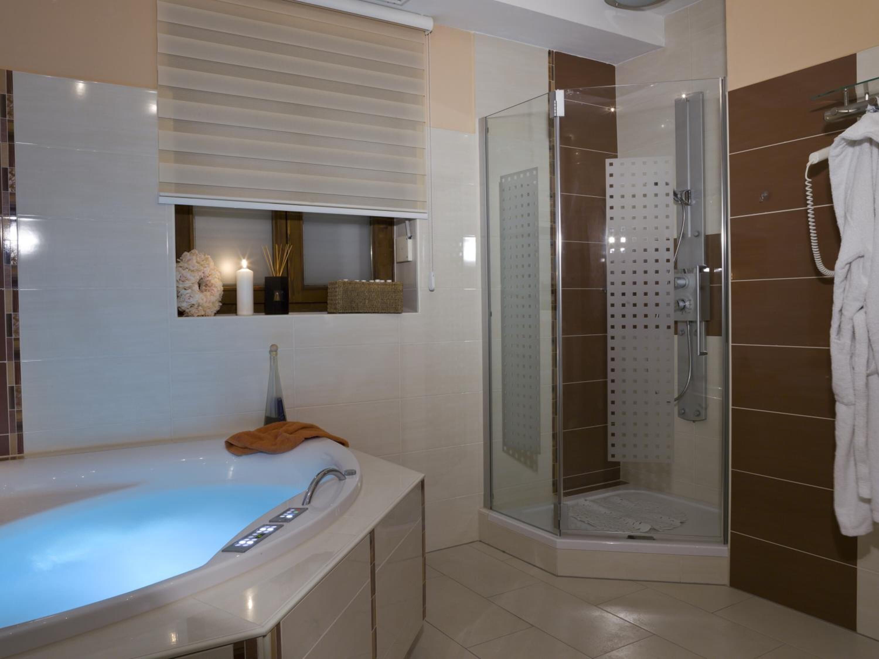 Een moderne badkamer met een badkuip, een douche met glazen wand en een handdoekhouder.